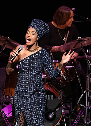 Jazzmeia Horn performs, at Royce Hall on November 9, 2018, as part of Terri Lyne Carrington's tribute to music Joni Mitchell, Tina Turner and Nancy Wilson. (Carrington in background) (c) Reed Hutchinson 2018